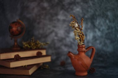 Güzel sanatlar konsepti. Gri arka planlarda çiçekli ve küresi olan taşralı kitaplara sahip natürmort yaşam.