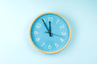 Mavi arkaplanda renkli duvar saatinin kapanışı. Plastik duvar saatinin minimalist düz görüntüsü .