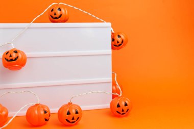 Turuncu arka planda küçük korkutucu balkabakları olan beyaz tahta. Cadılar Bayramı teması.