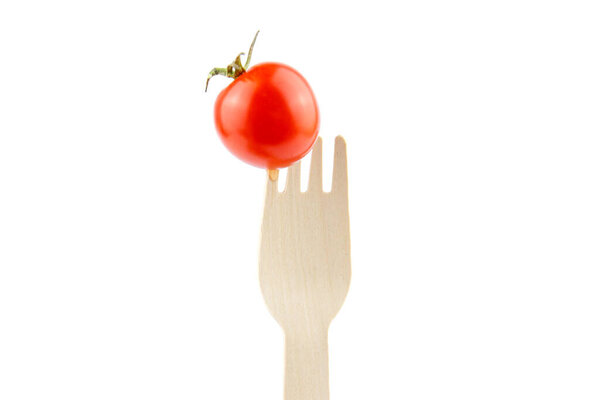 Tomato cherry on a wooden fork on a white background. Healthy food concept.