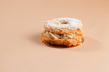 Bej renkli arka plan ile Fransız tatlı paris-brest. Makro paris-brest kadar kapatın. Pastel arka plan kopya alanı metni ile. 
