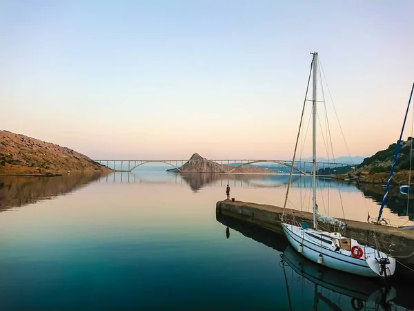 Small yacht moored near jetty during sunset