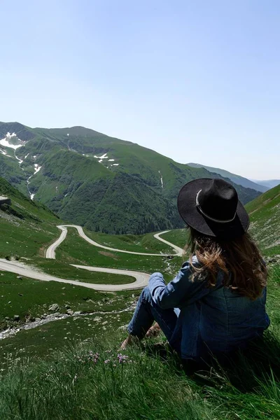 Dziewczyna Siedzi Wzgórzu Patrząc Drogi Transfagarasan Rumunii — Zdjęcie stockowe