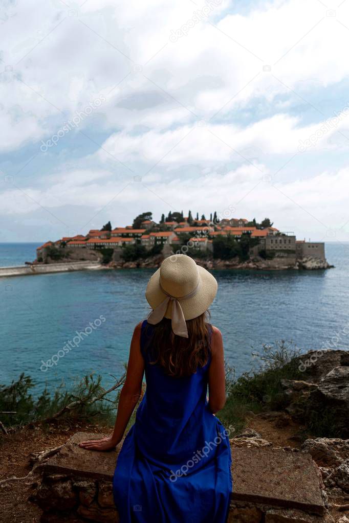 rear view of woman in hat looking at Sveti Stefan in Montenegro