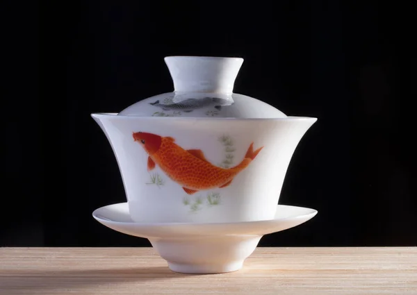 Taça de porcelana chinesa gaiwan com peixe no fundo preto — Fotografia de Stock