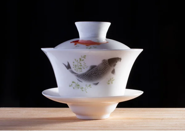 Taça de porcelana chinesa gaiwan com peixe no fundo preto — Fotografia de Stock