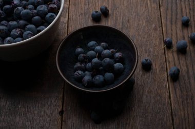 Eski ahşap masada bir kase yaban mersini. Düz kat. Koyu.