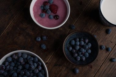 Bir bardak süt, bir fincan yaban mersini, bir fincan yoğurt ve eski ahşap masanın üzerinde devedikeni dalı. Düz yatıyordu