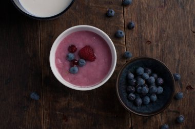 Bir bardak süt, bir fincan yaban mersini, eski ahşap masada böğürtlenli yoğurt. Düz yatıyordu