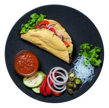 Üst Manzara. İçi besleyici ve siyah tabakta salsa soslu sıcak taco.