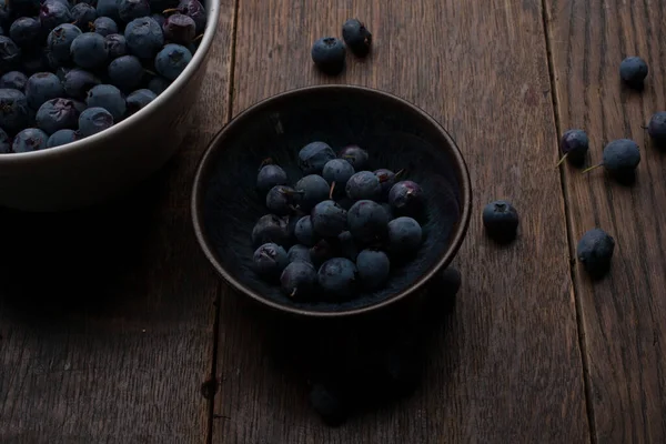 Eski ahşap masada bir kase yaban mersini.