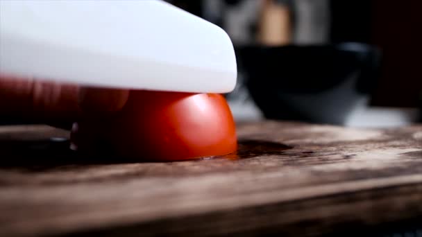 Cięcie pomidora białym ceramicznym nożem na wiejskiej drewnianej desce — Wideo stockowe