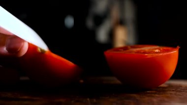 Kırsal bir tahta üzerinde beyaz seramik bıçakla domates doğramak