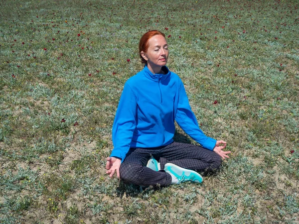 Yoga, meditasyon yapıyor, lotus poz yeşil çimenlerin üzerinde oturan Olgun kadın.