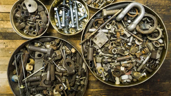 Mix of rusty auto scrap including nuts, bolts, springs, washers, cotter pins, collected in the old metallic can.