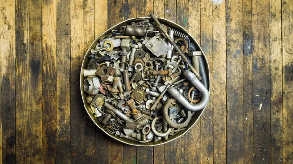 Mix of rusty auto scrap including nuts, bolts, springs, washers, cotter pins, collected in the old metallic can.