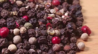 Bambu kesme tahtasındaki bir yığın renkli karabiber. Makro atış. Alan derinliğini daralt.