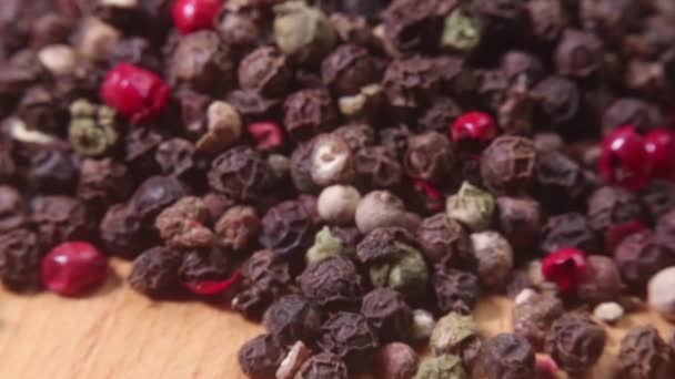 Closeup of a pile of colored peppercorns on a bamboo cutting board. Macro shot. Narrow depth of field. — Stock Video