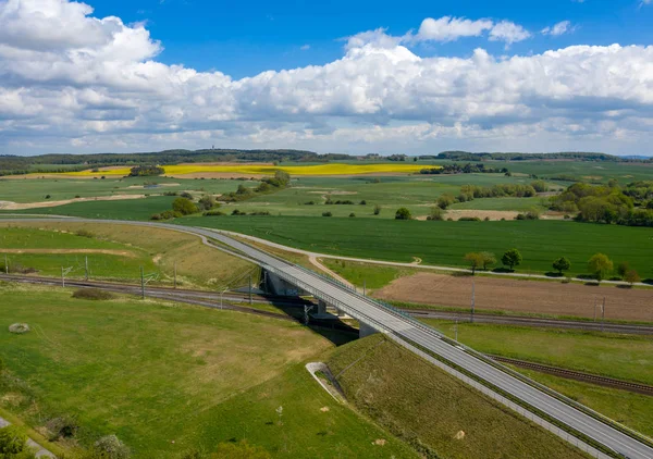 aerial image of agricultural fields and road bridge - railway track - springtime