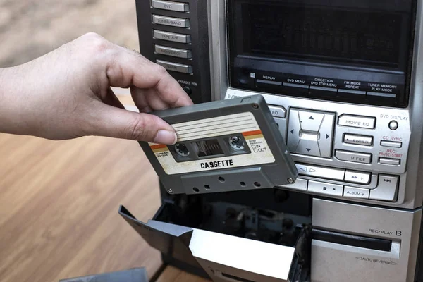 トップ デスク木製背景に古い昔ながらオーディオ テープ プレーヤーにカセットを入れて女性手 — ストック写真