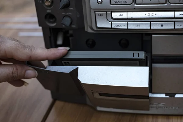 トップ デスク木製背景に古い昔ながらオーディオ テープ プレーヤーにカセットを入れて女性手 — ストック写真