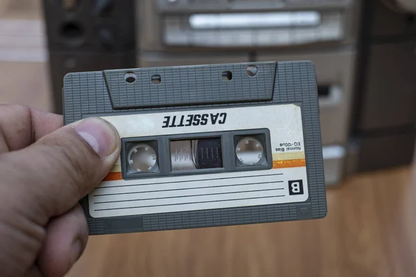 トップ デスク木製背景に古い昔ながらオーディオ テープ プレーヤーにカセットを入れて男の手 — ストック写真
