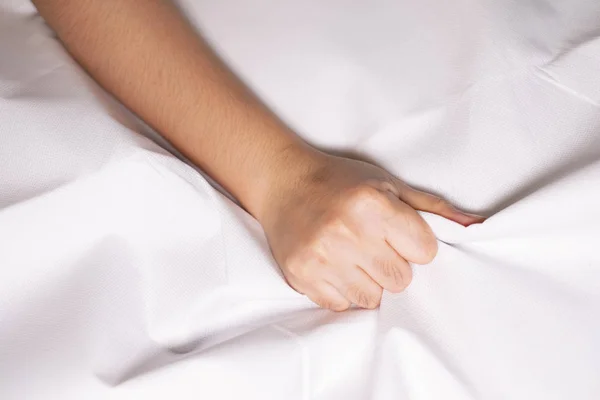 Woman hand squeezing bed sheets color white