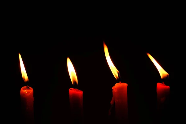四个明火蜡烛明亮地燃烧在黑色背景 — 图库照片