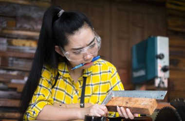 Ahşap atölyesinde masada işaretleri yaparken cetvel ve kalem tutan kadın