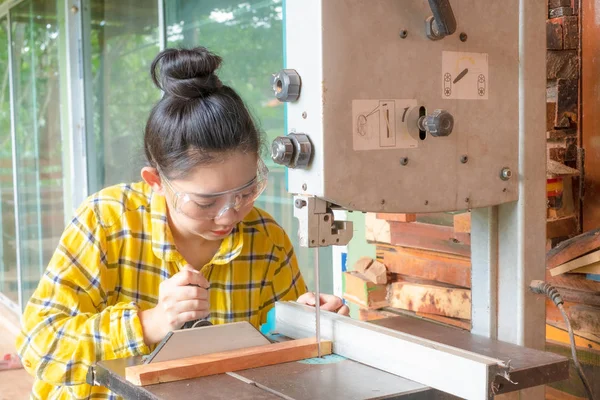 Mulheres de pé é artesanato de madeira cortada em um banco de trabalho — Fotografia de Stock