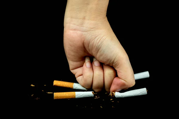 Women fist crushing cigarettes over black Background — Stock Photo, Image