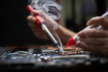 Yakın çekim el teknisyeni, kırık dizüstü bilgisayarı elektrik lehimleme sistemiyle tamir ediyor.