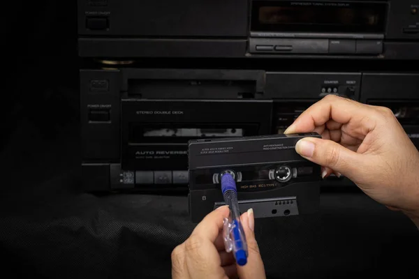 閉じる女性手を使用してペン巻き戻しカセットテープコンパクトで古い再生されたオーディオテープバックグラウン — ストック写真