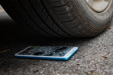 Ön ve arka planda bir araba lastiğini hareket ettirmekten dolayı akıllı telefon ekranı patlak.