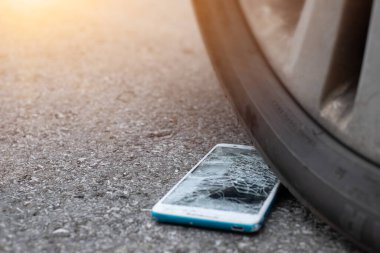 Ön ve arka planda bir araba lastiğini hareket ettirmekten dolayı akıllı telefon ekranı patlak.