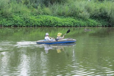 Evli bir çift bir yaz gününde Nehri üzerinde şişme bir kayık üzerinde yüzüyor.