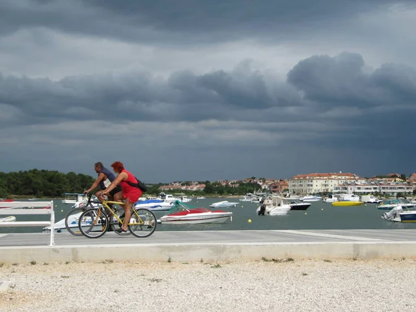 Een bejaarde echtpaar met een fiets aan de waterkant van Medulin. Kroatië, Primorje-Gorski Kotar, Medulin - 18 juli 2010. — Stockfoto