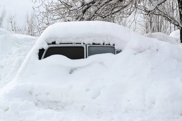 The car, covered with thick layer of snow. Negative consequence of heavy snowfalls. parked cars covered with snow during snowing in winter time.