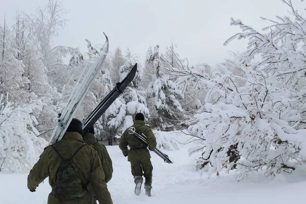 military uniform running with skis in the winter forest.