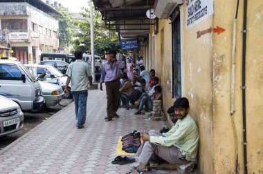 Birçok Hint zavallı erkek kaldırım yolun yakınında oturmak ve bir şey satmak. Hindistan, Goa-29 Ocak 2009.