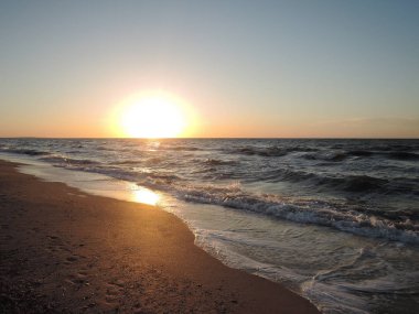 Yumuşak deniz dalgaları altın arkaplanı kaplıyor. Gün batımı, gün doğumu, güneş