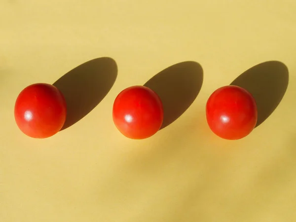 Tres Tomates Cherry Encuentran Ordenadamente Sobre Fondo Amarillo —  Fotos de Stock