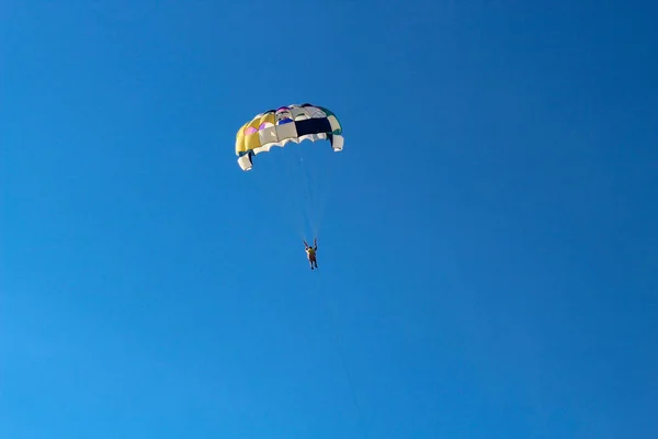 Parasailing vodní zábavu. Krásné světle modré oblohy a barevný padák na kterém letí dospělého jedince — Stock fotografie