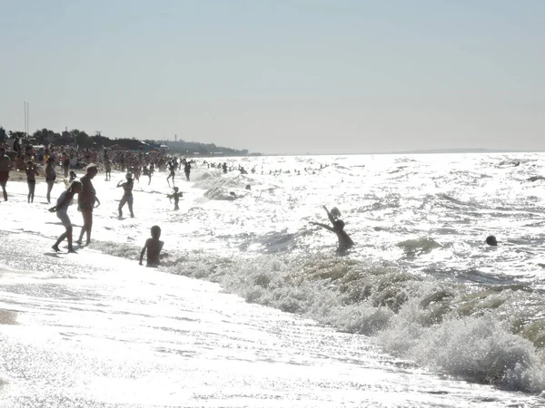 Personas salpicando en las olas furiosas en el mar en un día soleado — Foto de Stock
