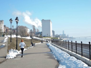 Bir kız bir beyaz spor üniformalı çalıştıran, bir bahar günü bahar deniz kıyısı çalışır devreye girer.