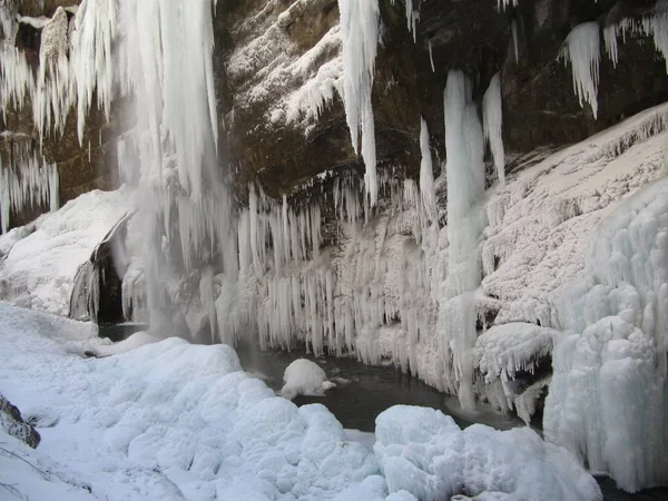 Enormes carámbanos en rocas de piedra cuelgan sobre el precipicio en medio del invierno . — Foto de Stock