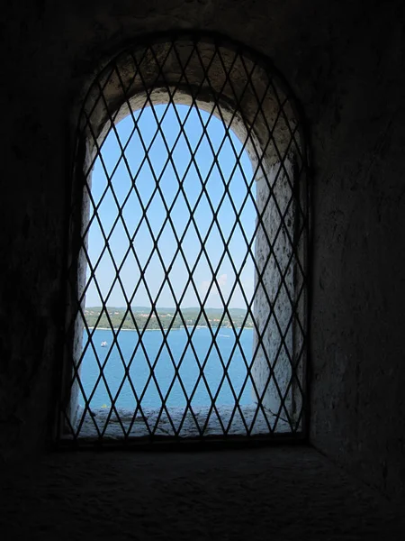 cell wall with a window with bars with sea view, interior perspective.