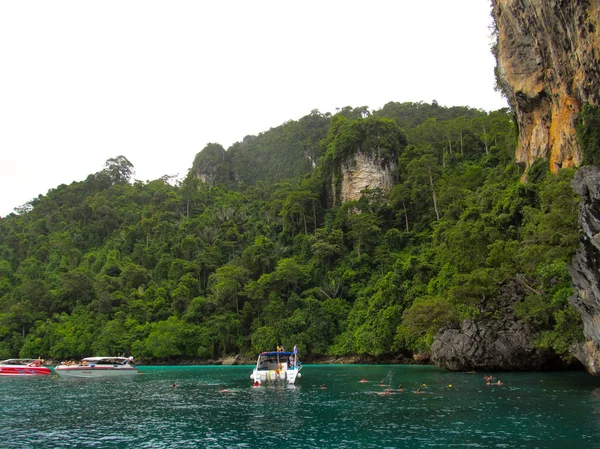 Petit bateau avec des touristes arrêtés près d'un énorme rocher afin que les touristes puissent comprendre l'océan et voir le monde sous-marin — Photo