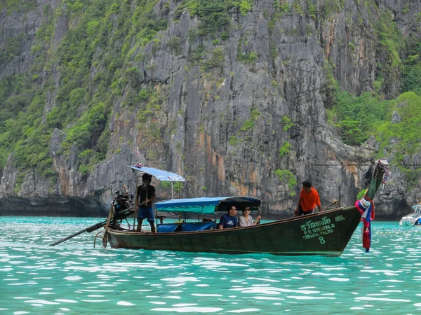 タイ人男性が経営する木造船が美しい美しい海岸沿いに数人の外国人観光客と一緒に航海している — ストック写真