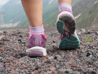 güzel renkli kadın Saucony koşu ayakkabıları, arka planda dağlar ile kadın bacakları arka görüşe Sneakers. Spor ve rahat ayakkabı kavramı. Rusya, Elbrus - Haziran 2019